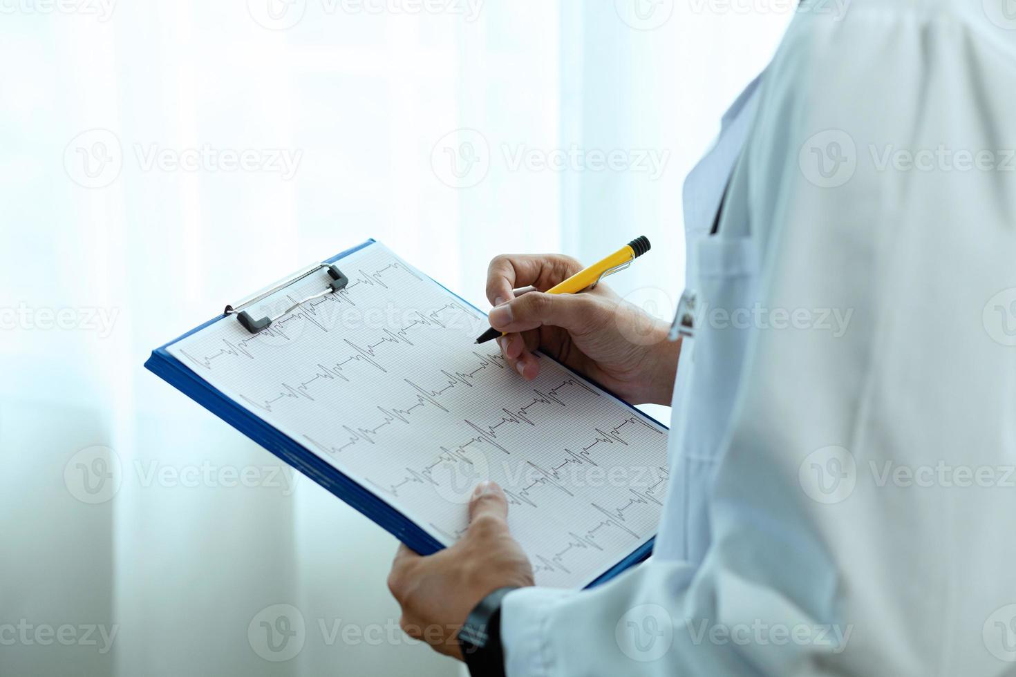 Close up. A beautiful Asian female doctor wearing a blue nurse uniform. Hold a pen and write something on the clipboard to write down patient information. photo