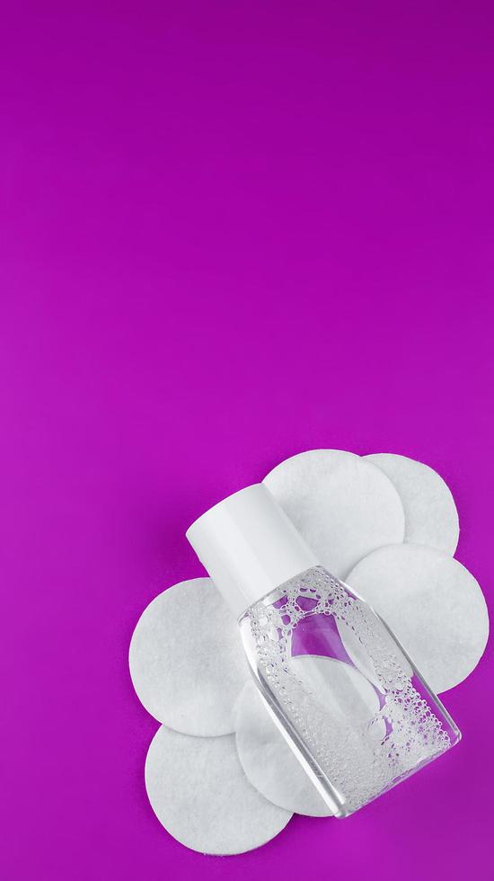 micellar water in a transparent bottle with cotton. Photographed from above against a pink background. photo