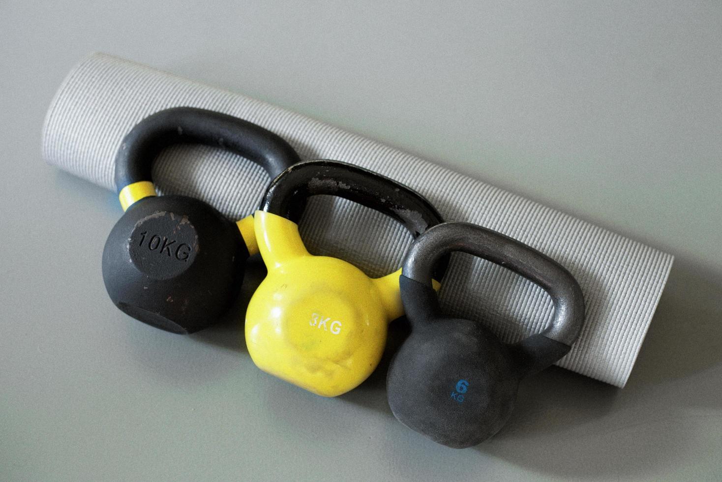 three kettlebells and grey yoga mat photo