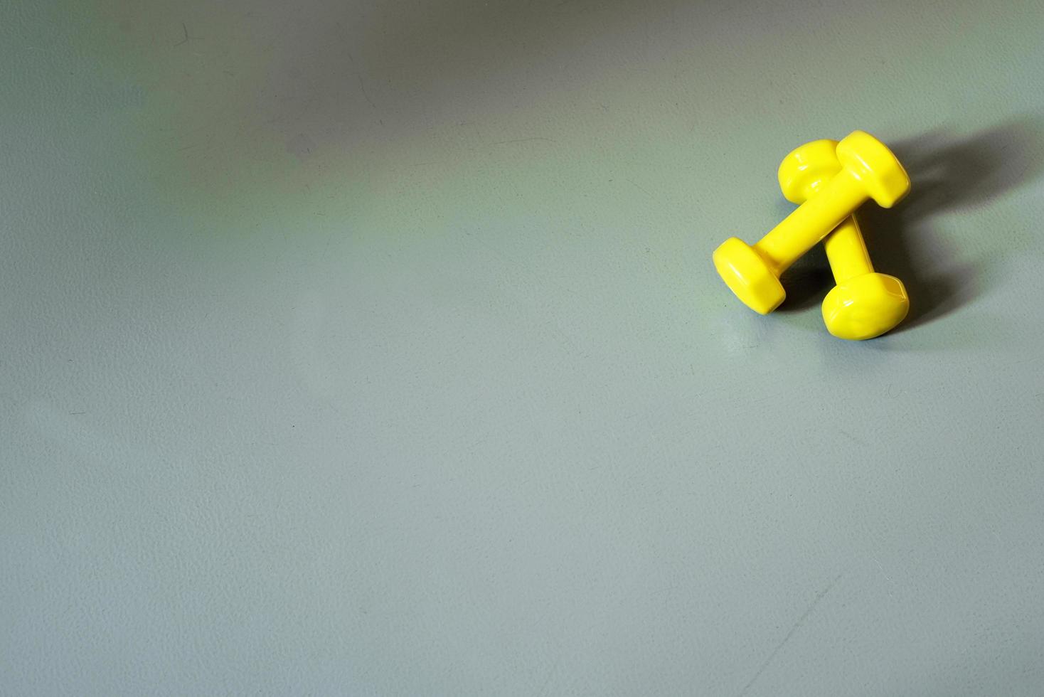 two yeallow dumbells on the grey yoga mat photo