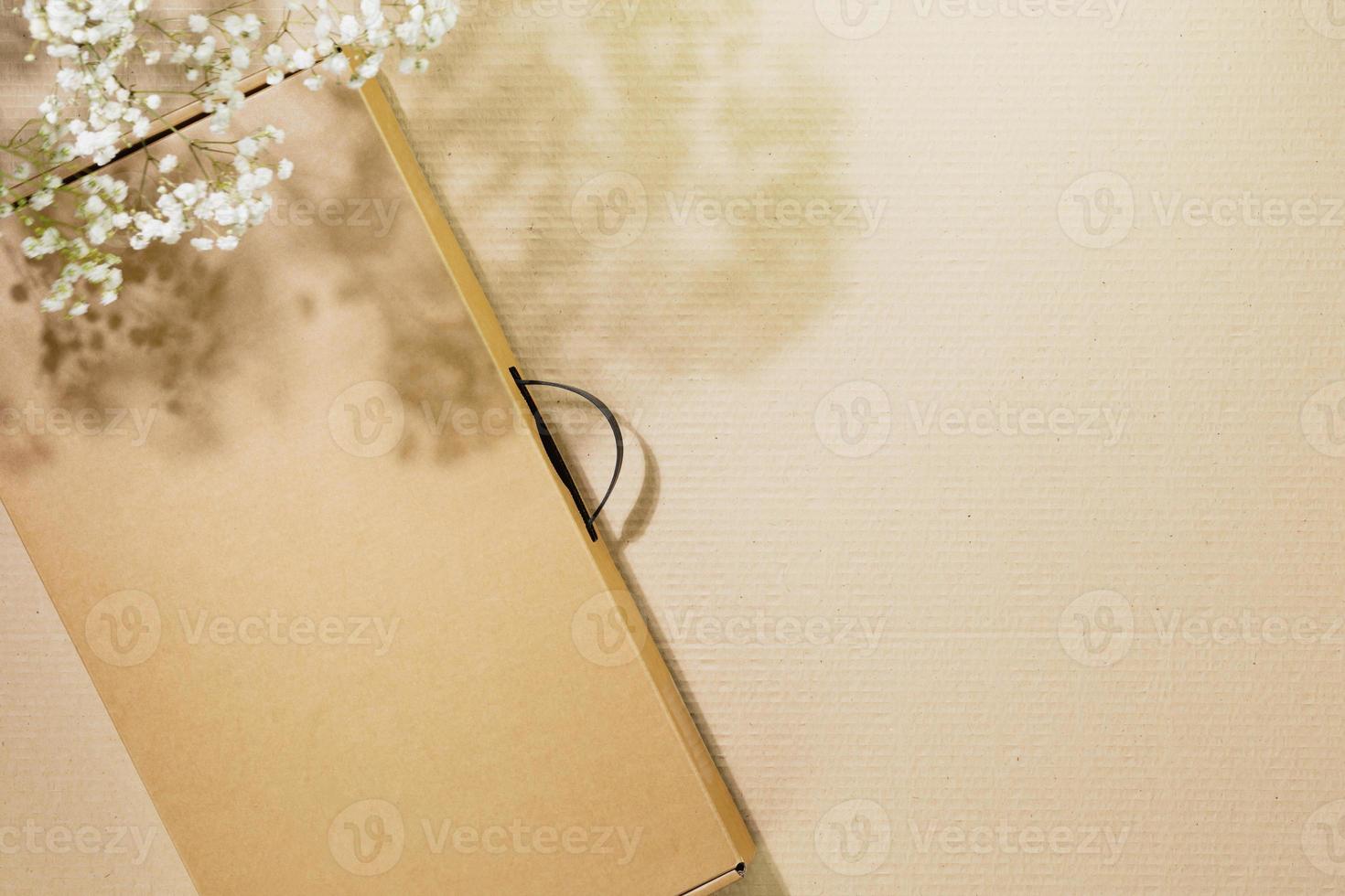 Cardboard box on cardboard background with white flowers and copy space photo