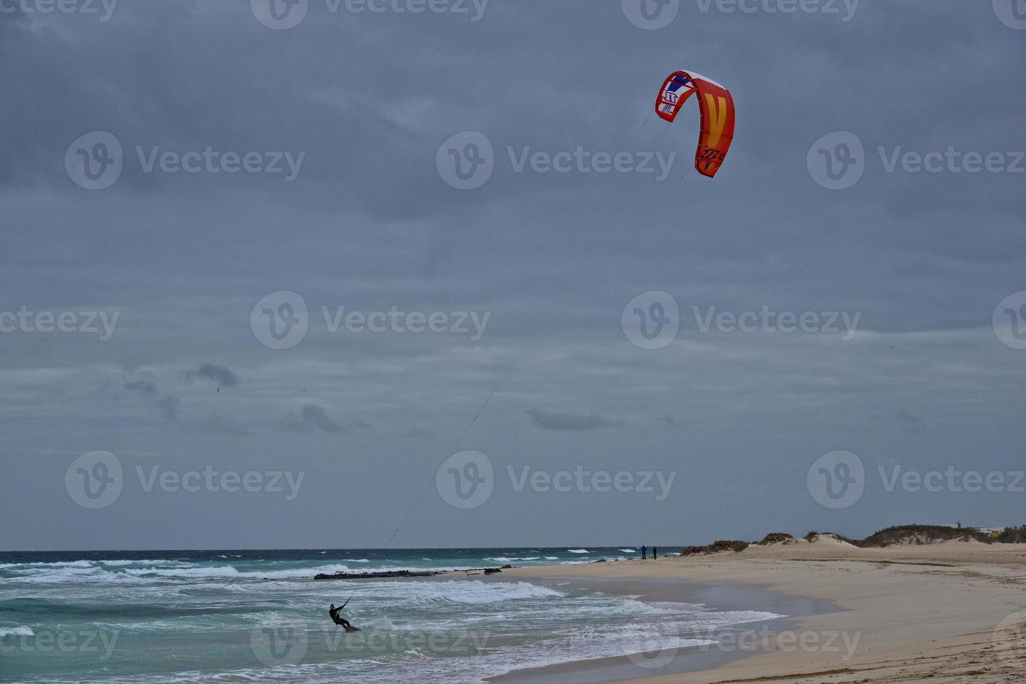 summer landscape with the ocean with dark cloudy waves and surfermi kit with parachutes floating on the shore photo