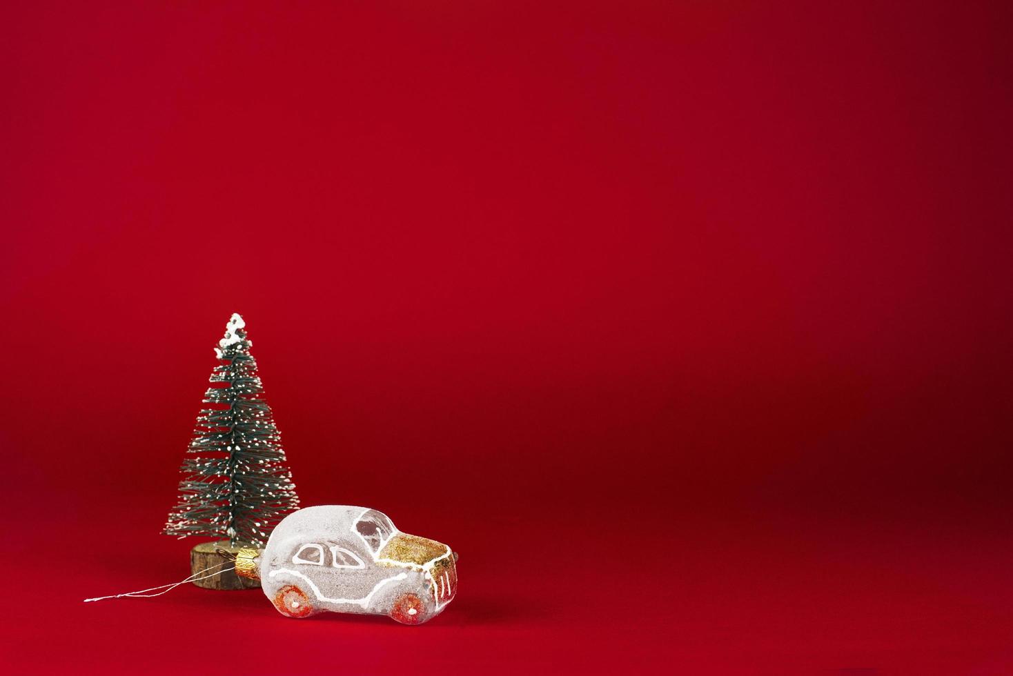 christmas card. White retro car next to a snow-covered Christmas tree on a red background. photo