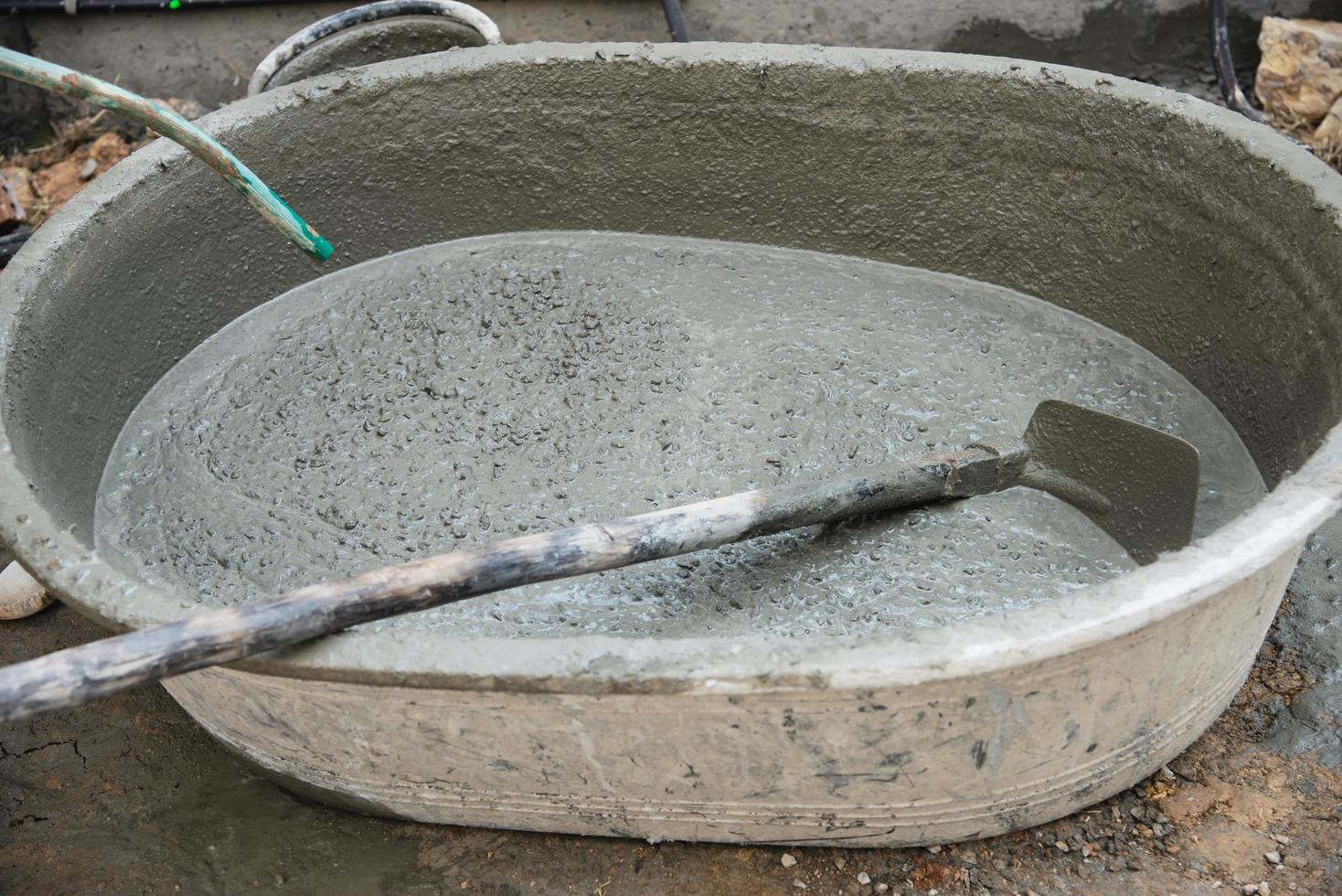 builder contractor man job mix concrete in industry work project, pouring pipe water into the big mixing tray in construction site as professional employment photo