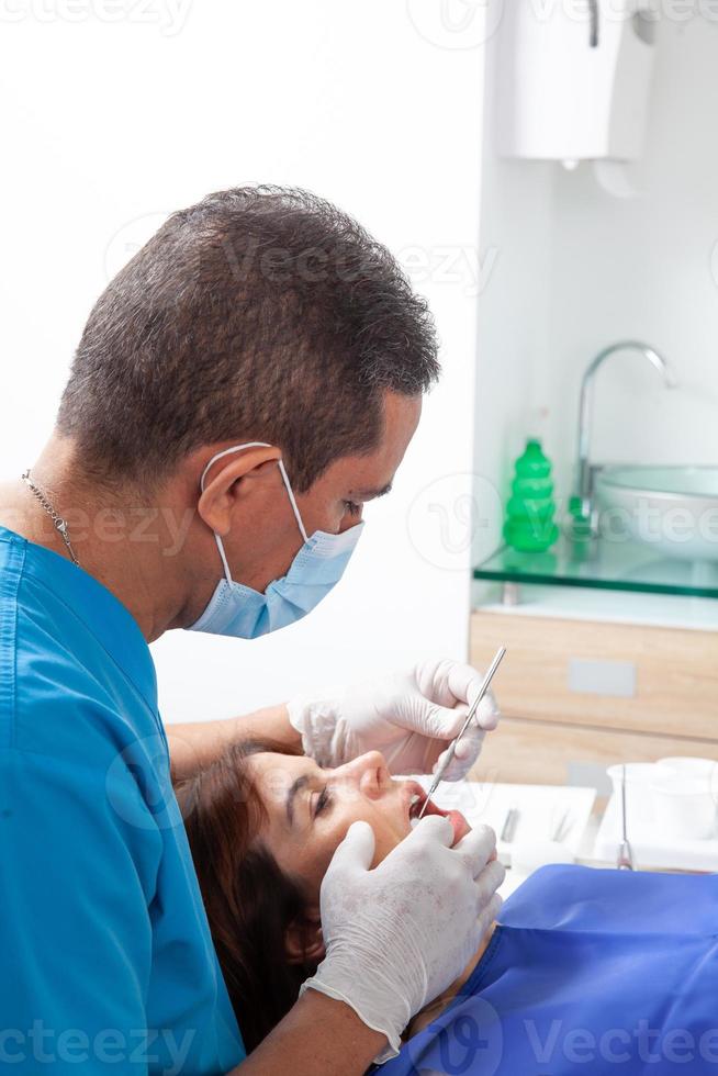 Male middle-aged dentist at his office with a female patient photo