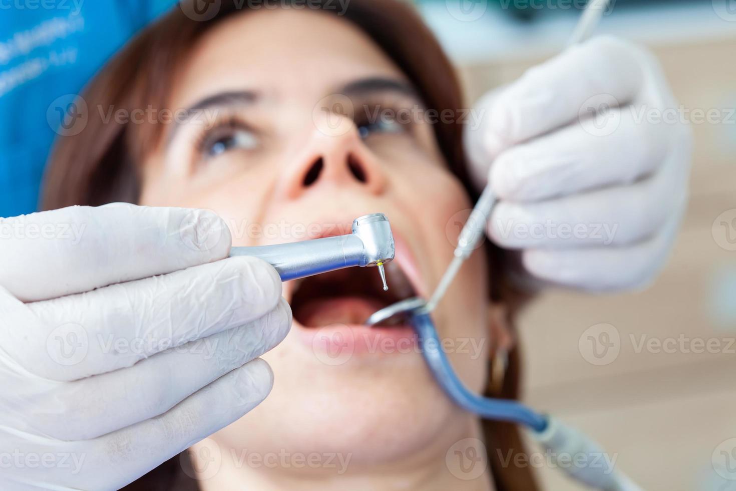 de cerca de un dental instrumentos siendo usado por el dentista durante un dental tratamiento para un hermosa mujer. foto