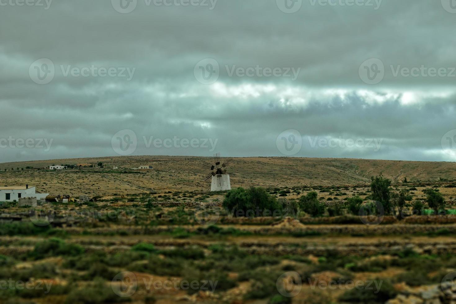 empty mysterious mountainous landscape from the center of the Canary Island Spanish Fuerteventura with a cloudy sky and original windmills photo