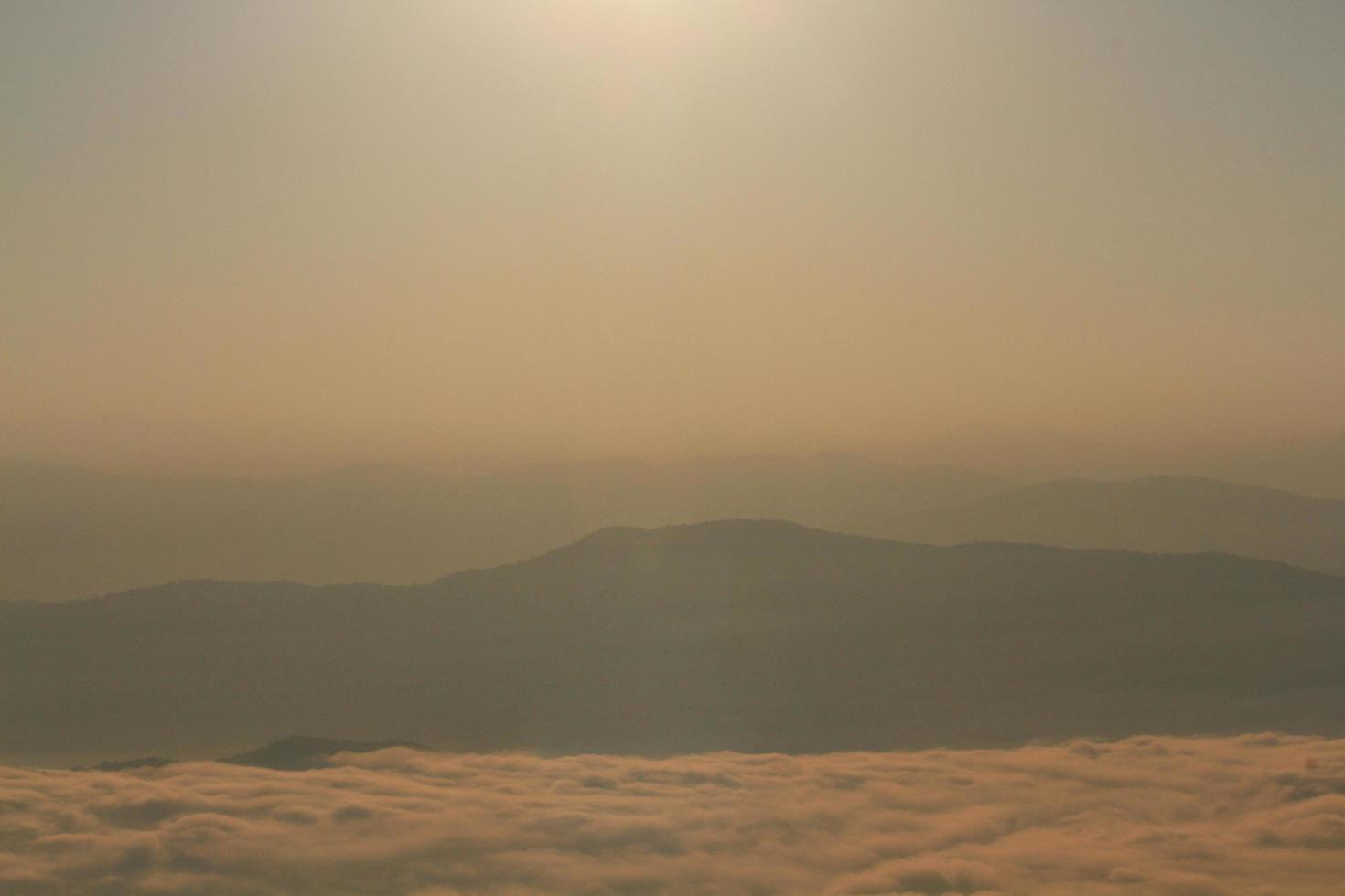 Beautiful golden natural sunlight and twiligh of sunrise shining to in the mist on valley of mountain in Thailand photo