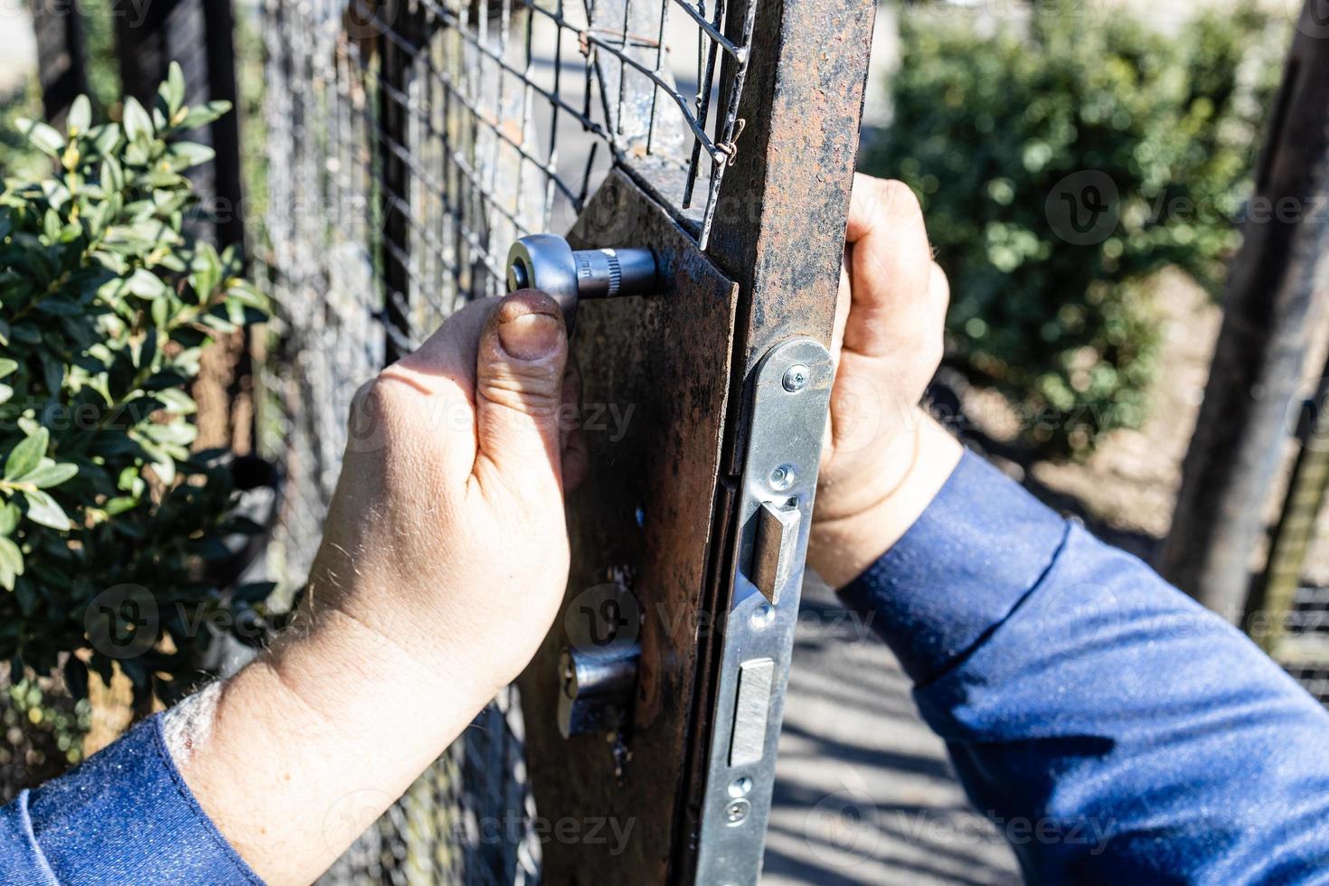 worker mounts new door lock in iron gate close up photo