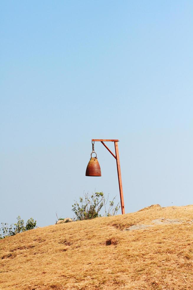 Old rusty bell with Dry grassland and wild with blue sky on the valley mountain at Doi Pha Tang hill in Thailand photo