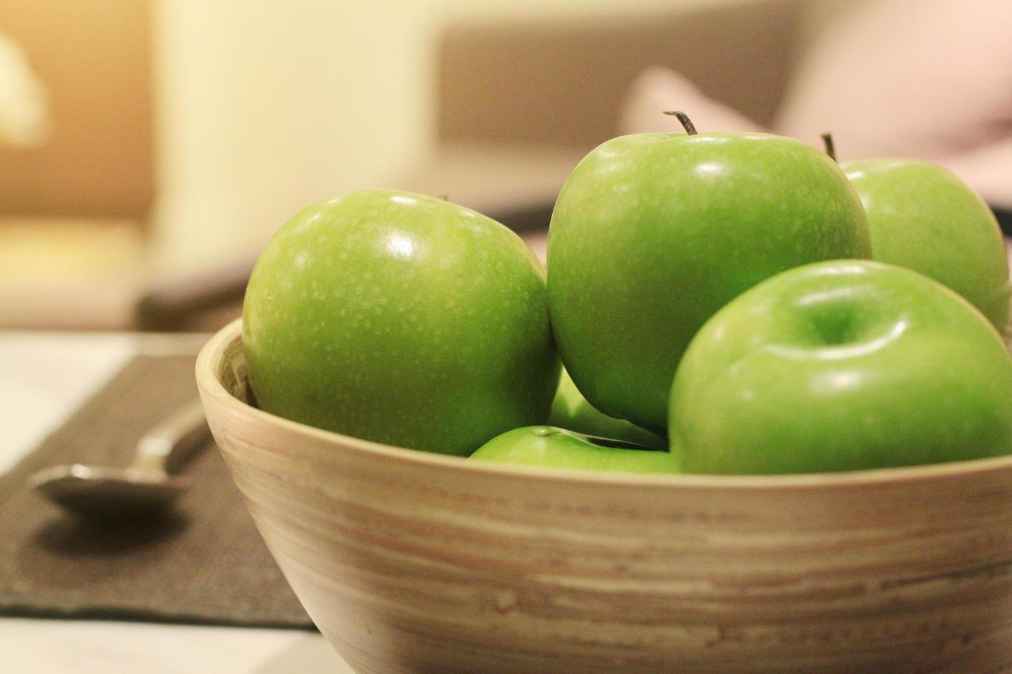 Freshness green apple in wood bowl decoration on dining table photo