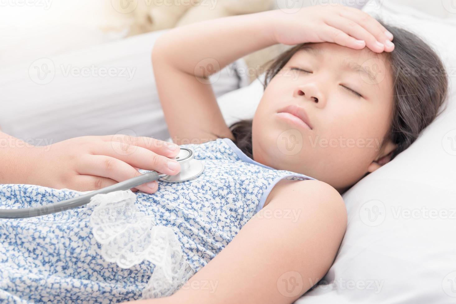 little hand doctor exams sick girl with stethoscope photo