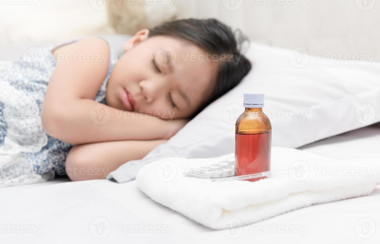 enfermo niña acostado en cama y medicina jarabe foto