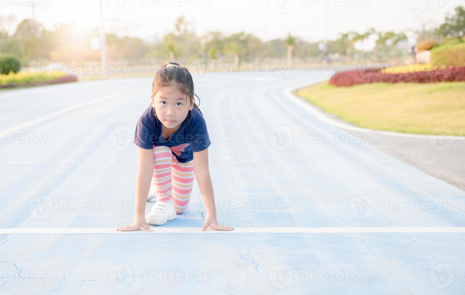 Cheerful cute girl in ready position to run on track photo