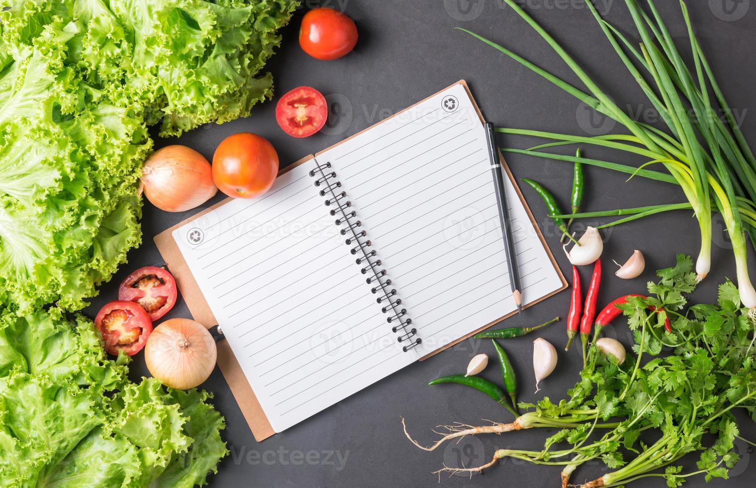 mix vegetables with blank notebook on black bcakground photo