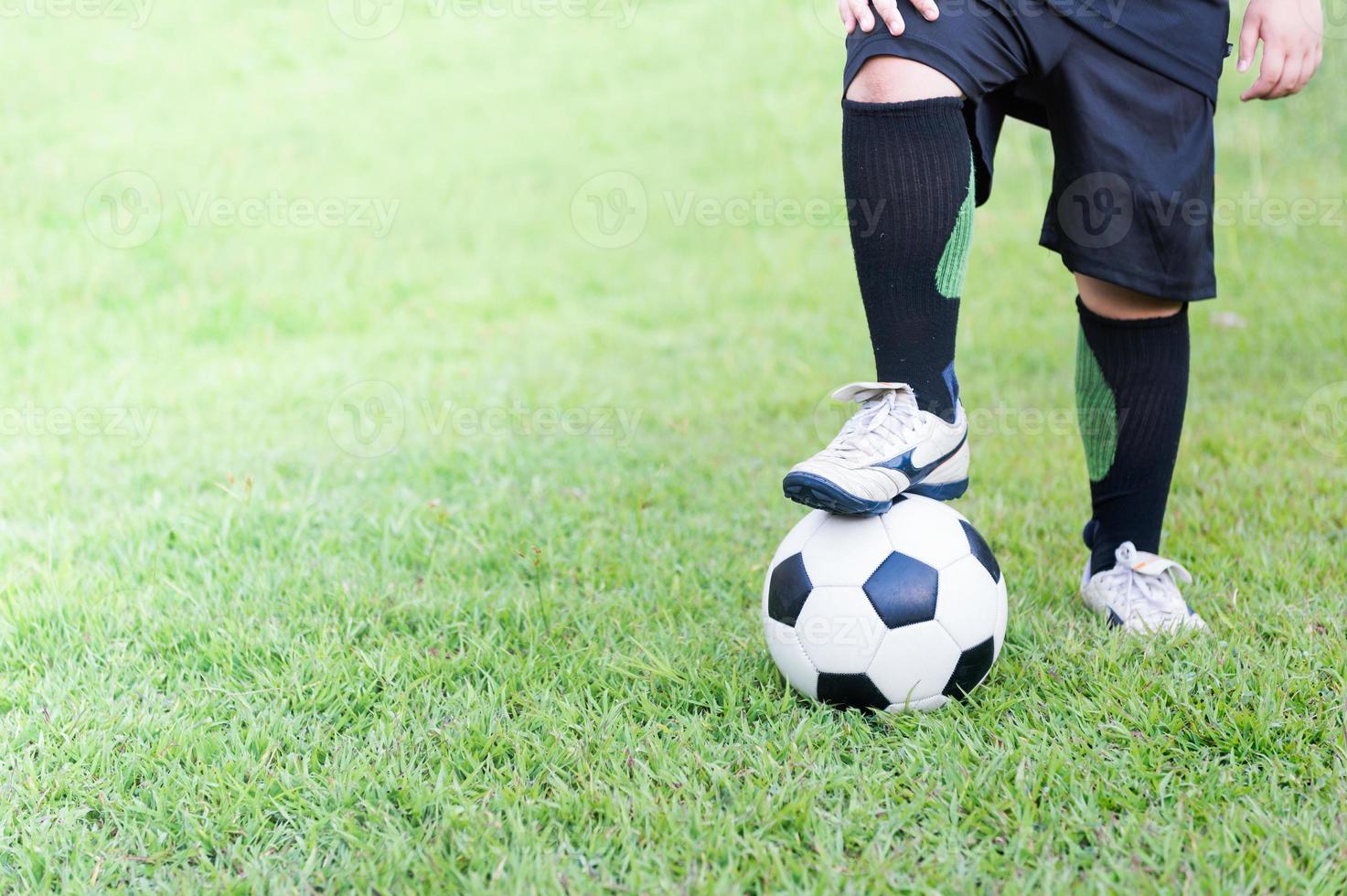 fútbol pelota con niño pies jugador en verde césped foto