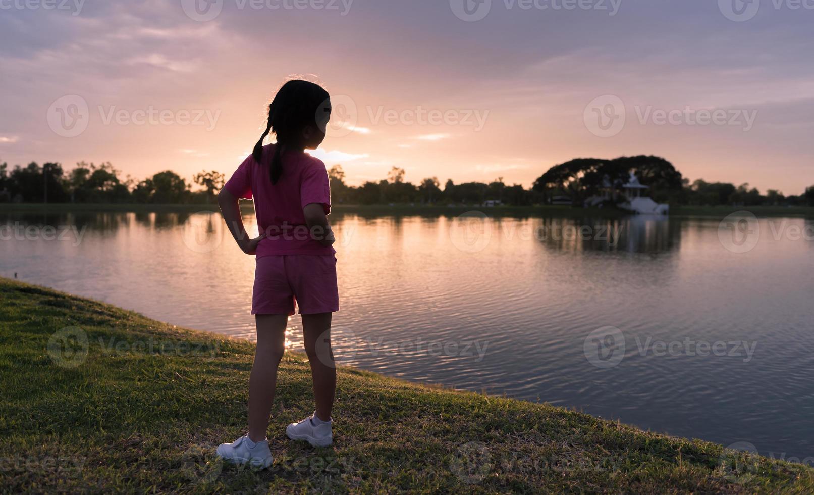 back side of little girl exercise on park with sunset photo