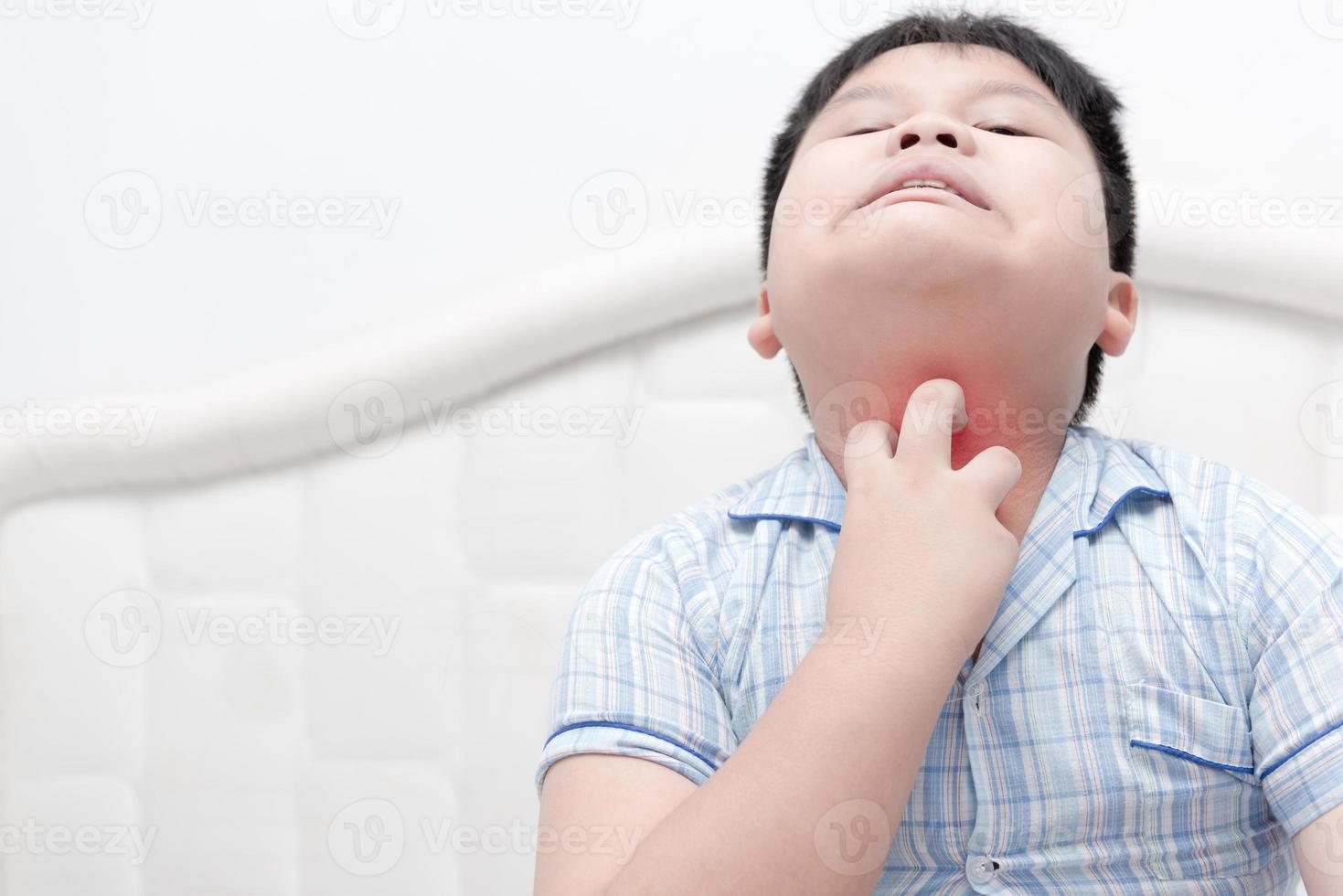 asian obese boy scratch the itch with hand on bed photo