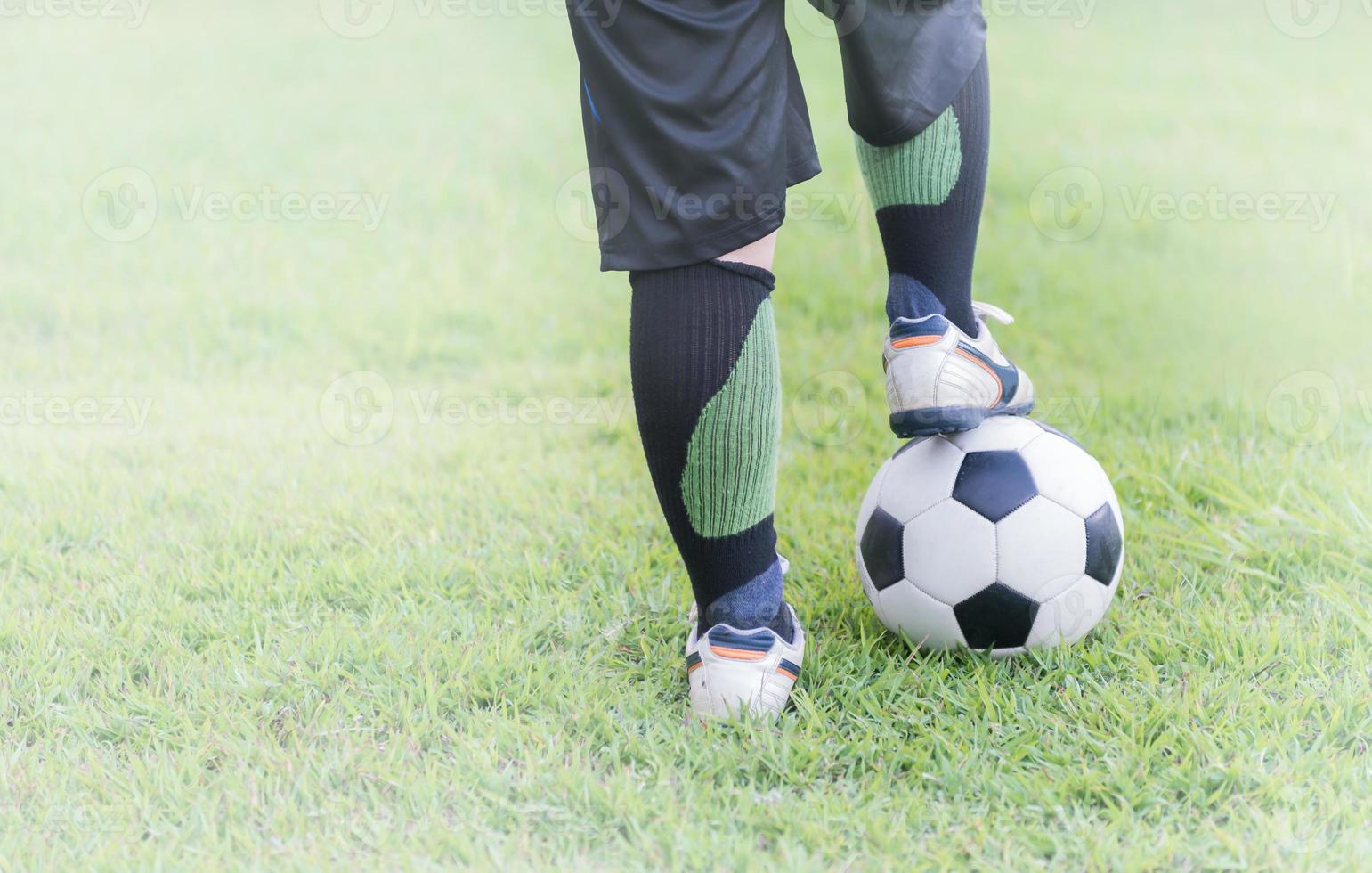 fútbol pelota con niño pies jugador en verde césped foto