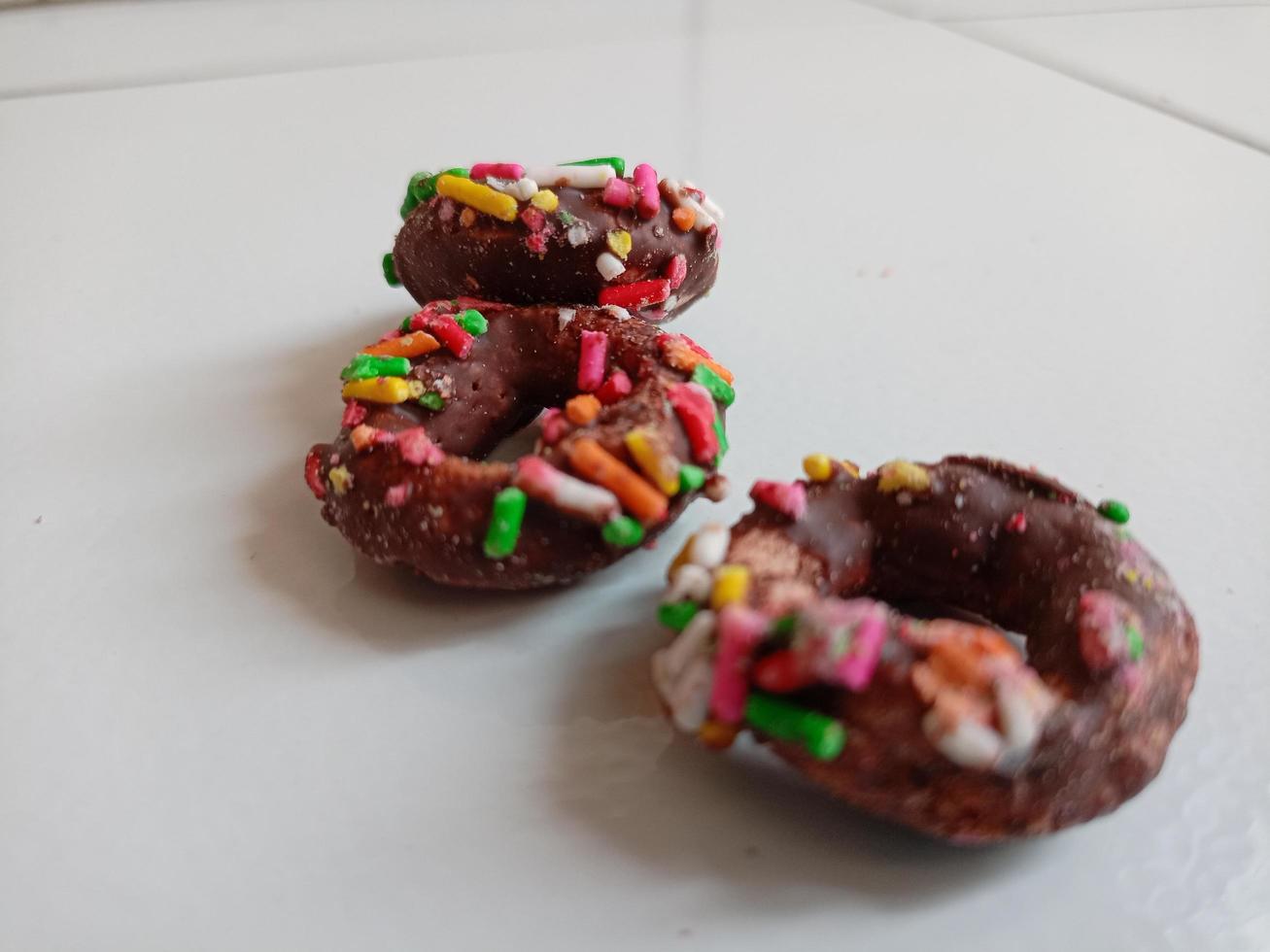 cerca arriba de vidriado rosquillas con brillante de colores rocía,aislado en un blanco antecedentes. foto