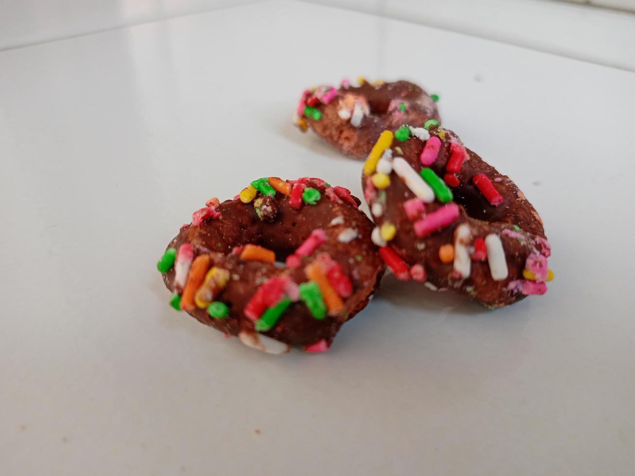 cerca arriba de vidriado rosquillas con brillante de colores rocía,aislado en un blanco antecedentes. foto