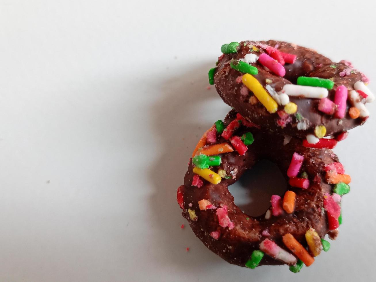 Close up of glazed doughnuts with bright colored sprinkles,isolated on a white background. photo