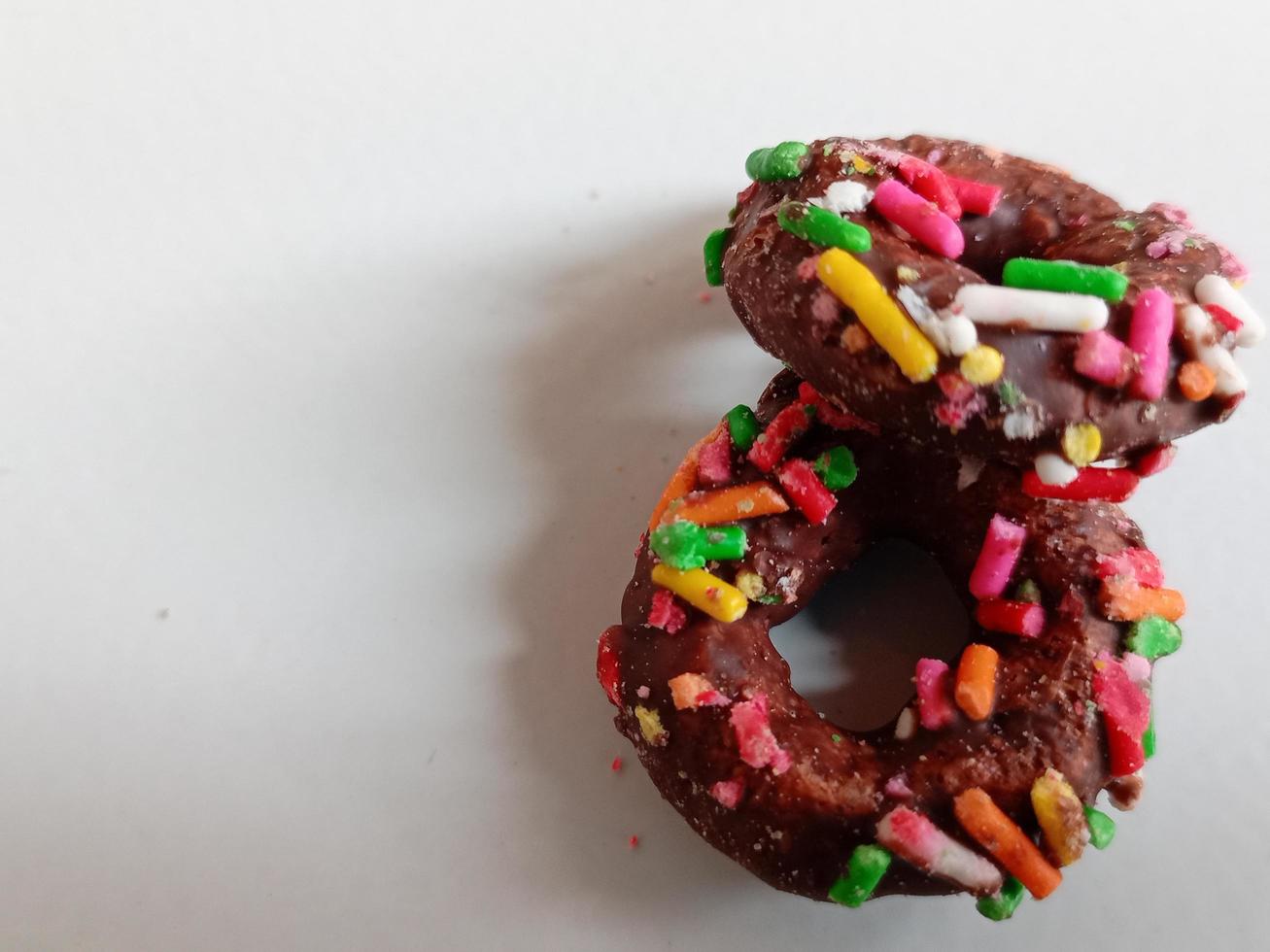 cerca arriba de vidriado rosquillas con brillante de colores rocía,aislado en un blanco antecedentes. foto