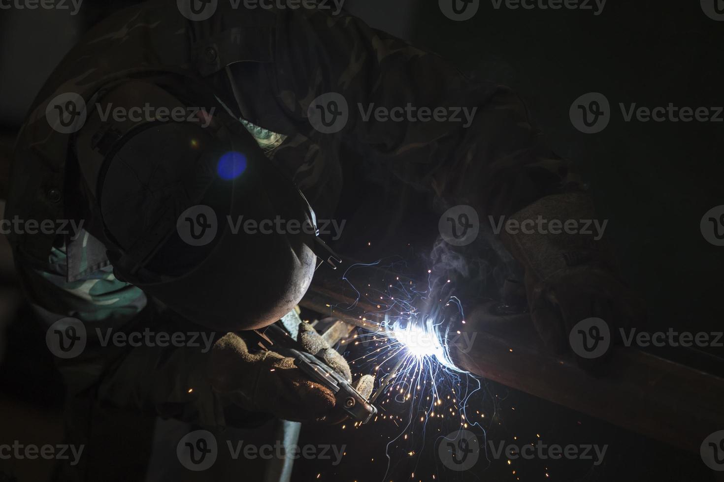 Welder at work. Man in a protective mask. The welder makes seams on the metal. Sparks and smoke when welding. photo