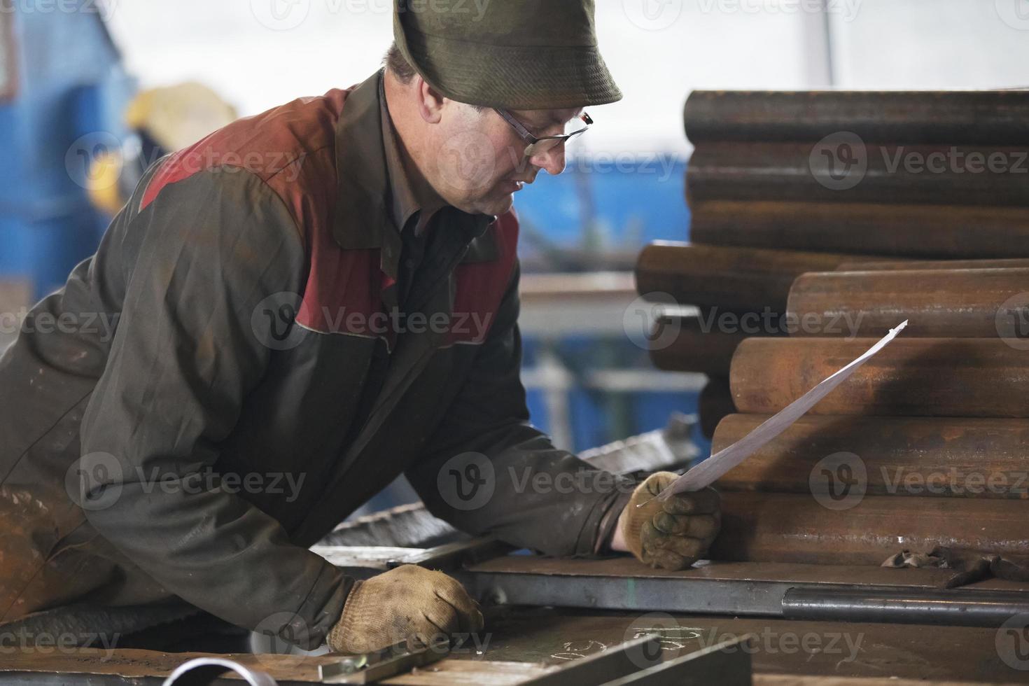 Metal industry. Worker in a factory with metal pipes.. photo