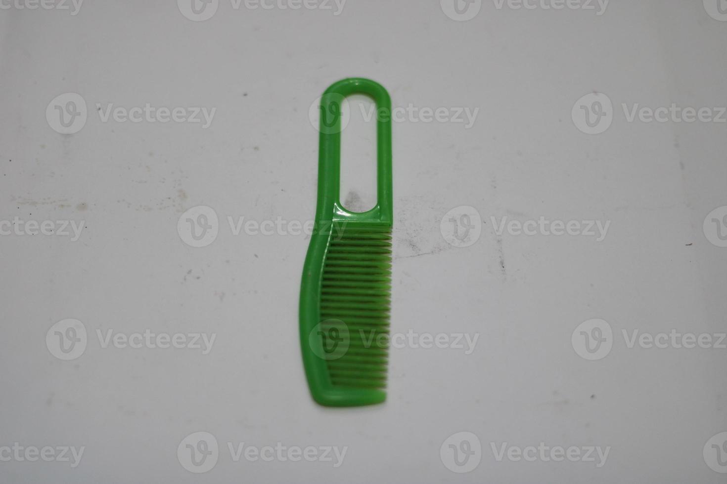 photo of a green hair comb made of plastic with a white background