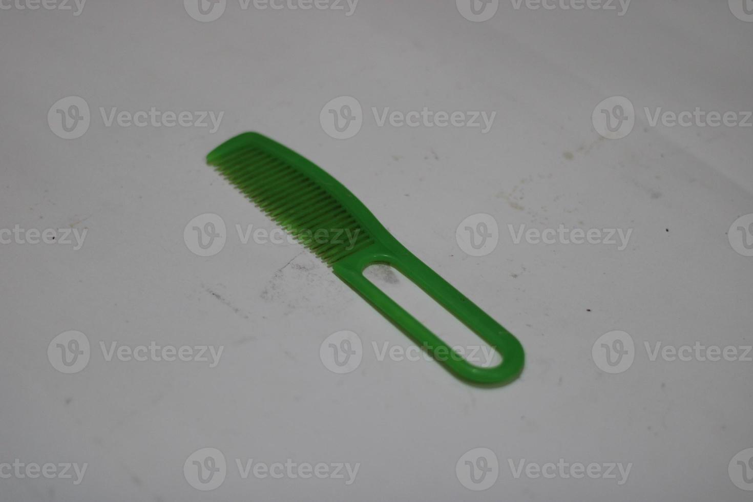 photo of a green hair comb made of plastic with a white background