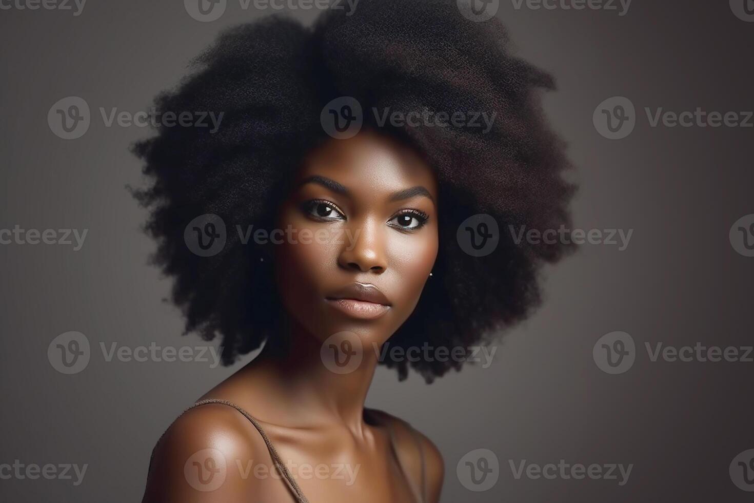 African girl with curly black hair. Studio portrait. Gray background. photo