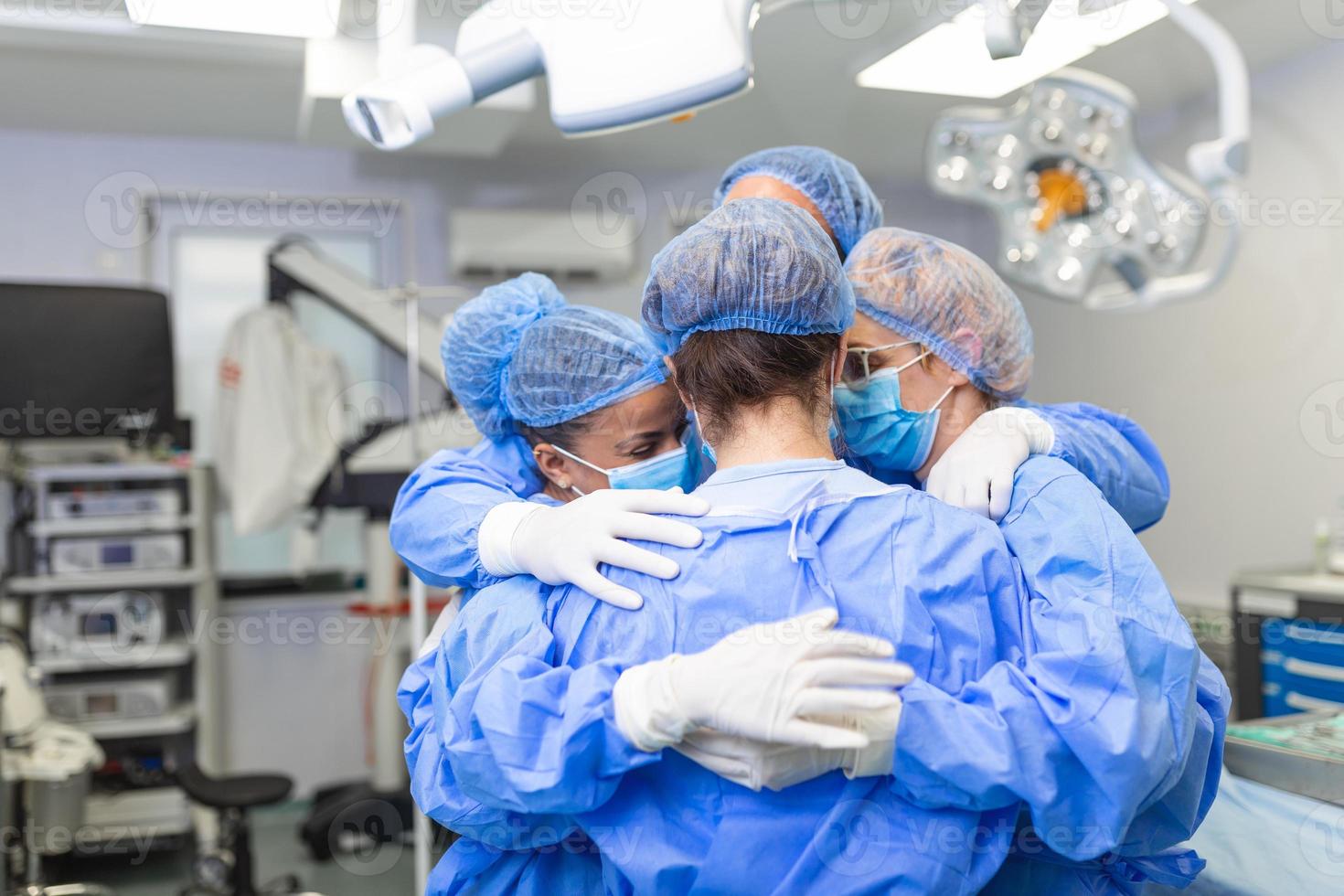 Medical professionals embracing each other in ICU. Doctors and nurses are in protective coveralls after successful treatment. They are at hospital during COVID-19. photo