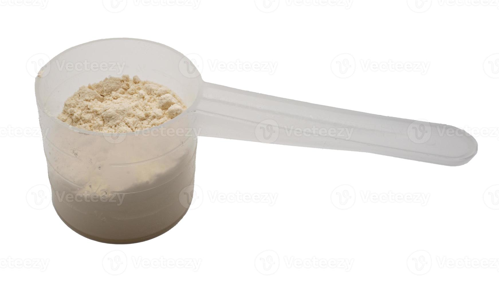 Whey protein powder in a measuring spoon isolated on white background. photo