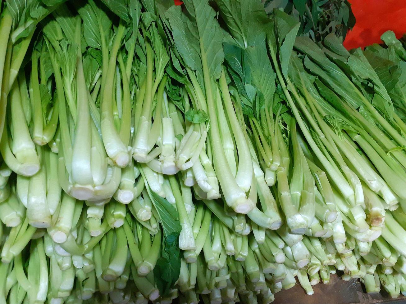 mostaza verduras son pulcramente arreglado en el estantería de un vegetal tienda. foto