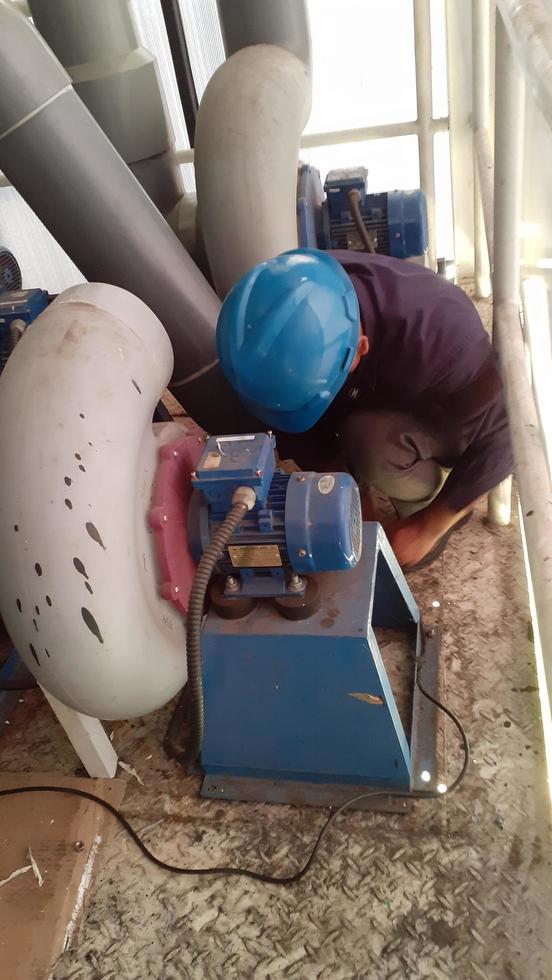 Jakarta Indonesia April 2023 A worker in a protective helmet and safety shoes repairing a pump blower. photo