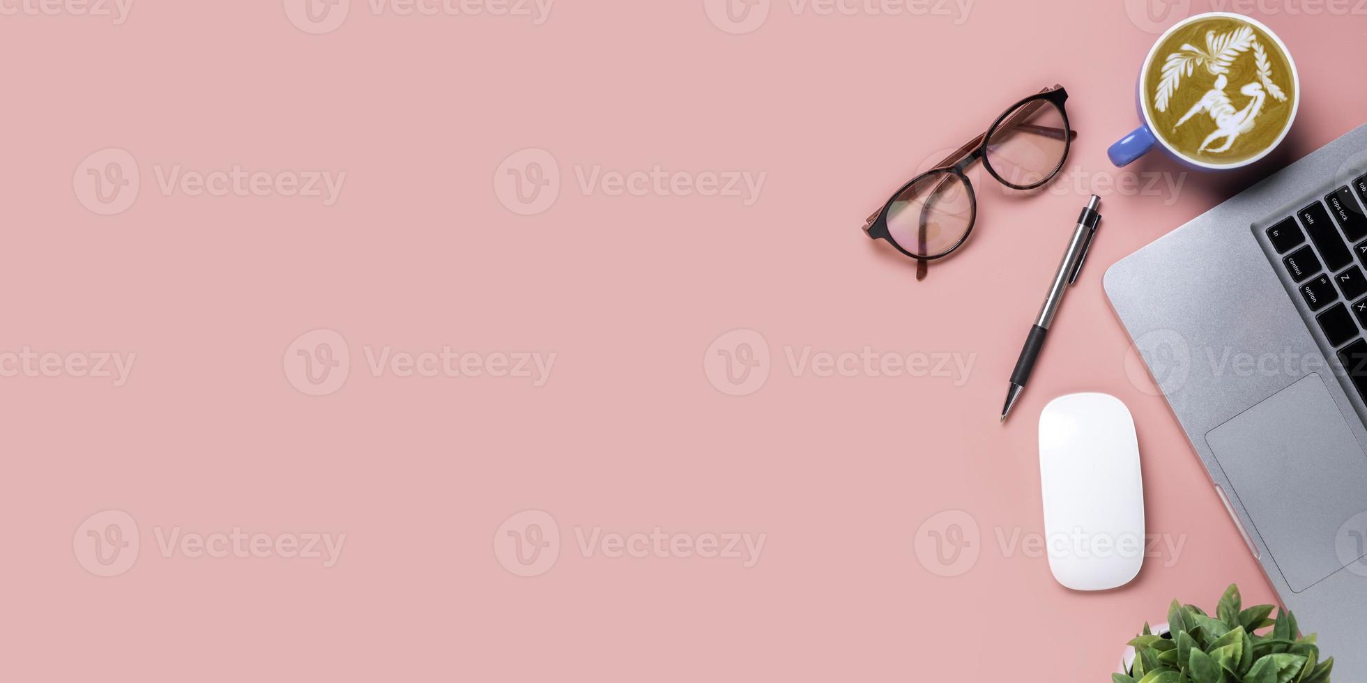 Office desk with computer, mouse, pen, eyeglass, Cup of coffee on pink background, Top view with copy space, Mock up. photo