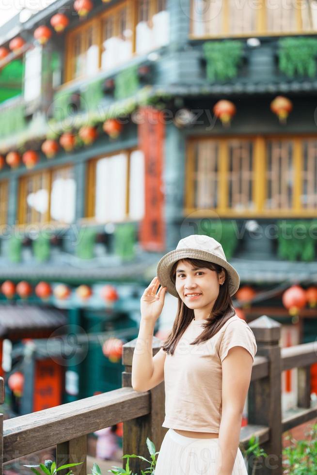 woman traveler visiting in Taiwan, Tourist with hat sightseeing in Jiufen Old Street village with Tea House background. landmark and popular attractions near Taipei city . Travel and Vacation concept photo