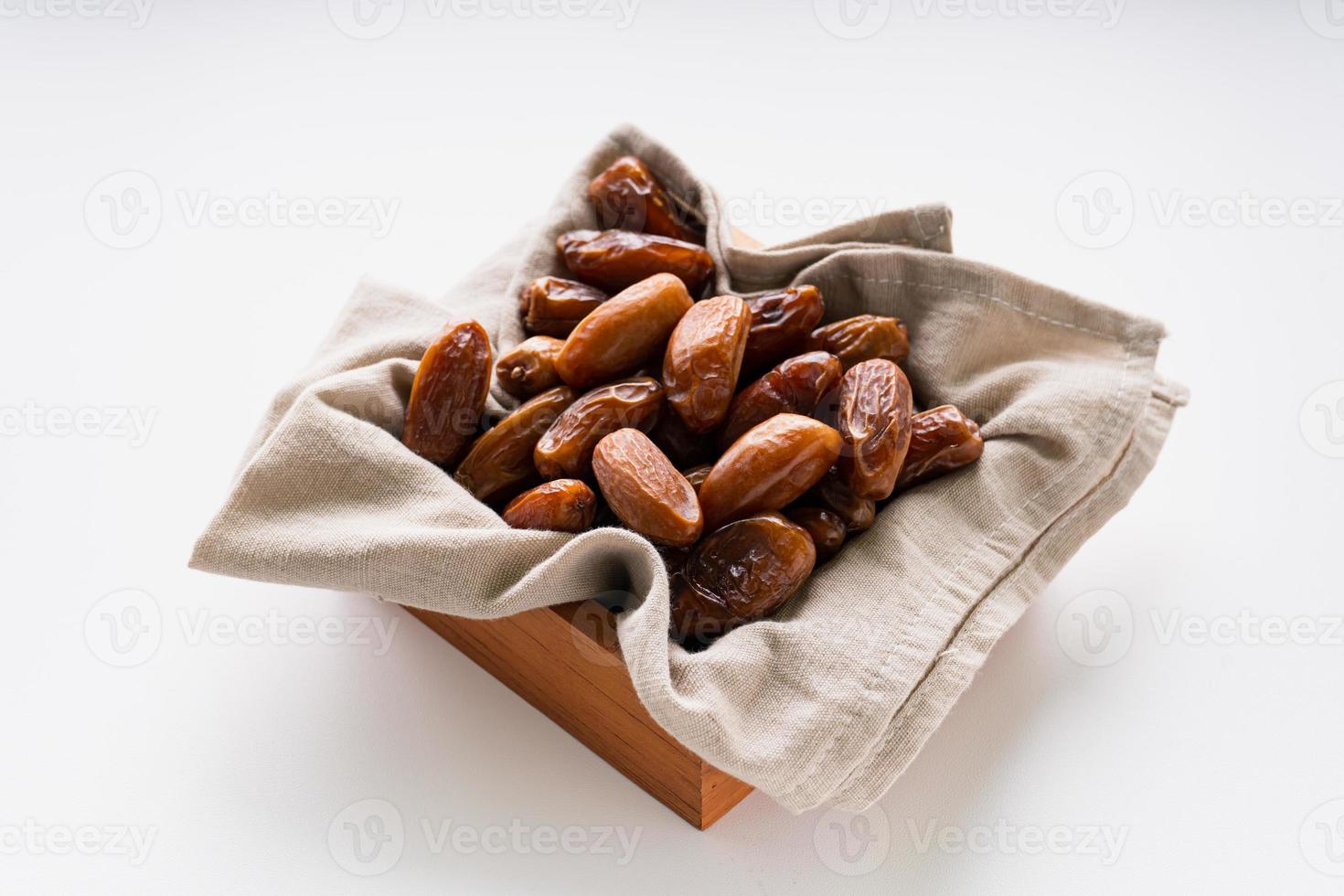 Dried dates fruit in wooden tray with soft napkin isolated on white background. photo