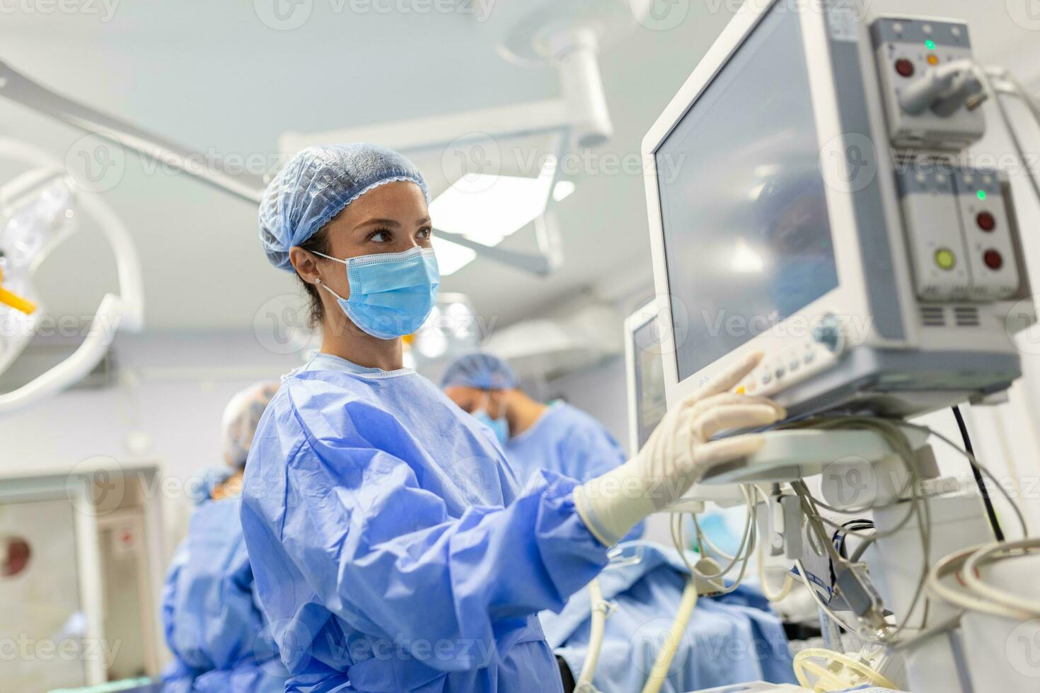 Anesthesiologist keeping track of vital functions of the body during cardiac surgery. Surgeon looking at medical monitor during surgery. Doctor checking monitor for patient health status. photo
