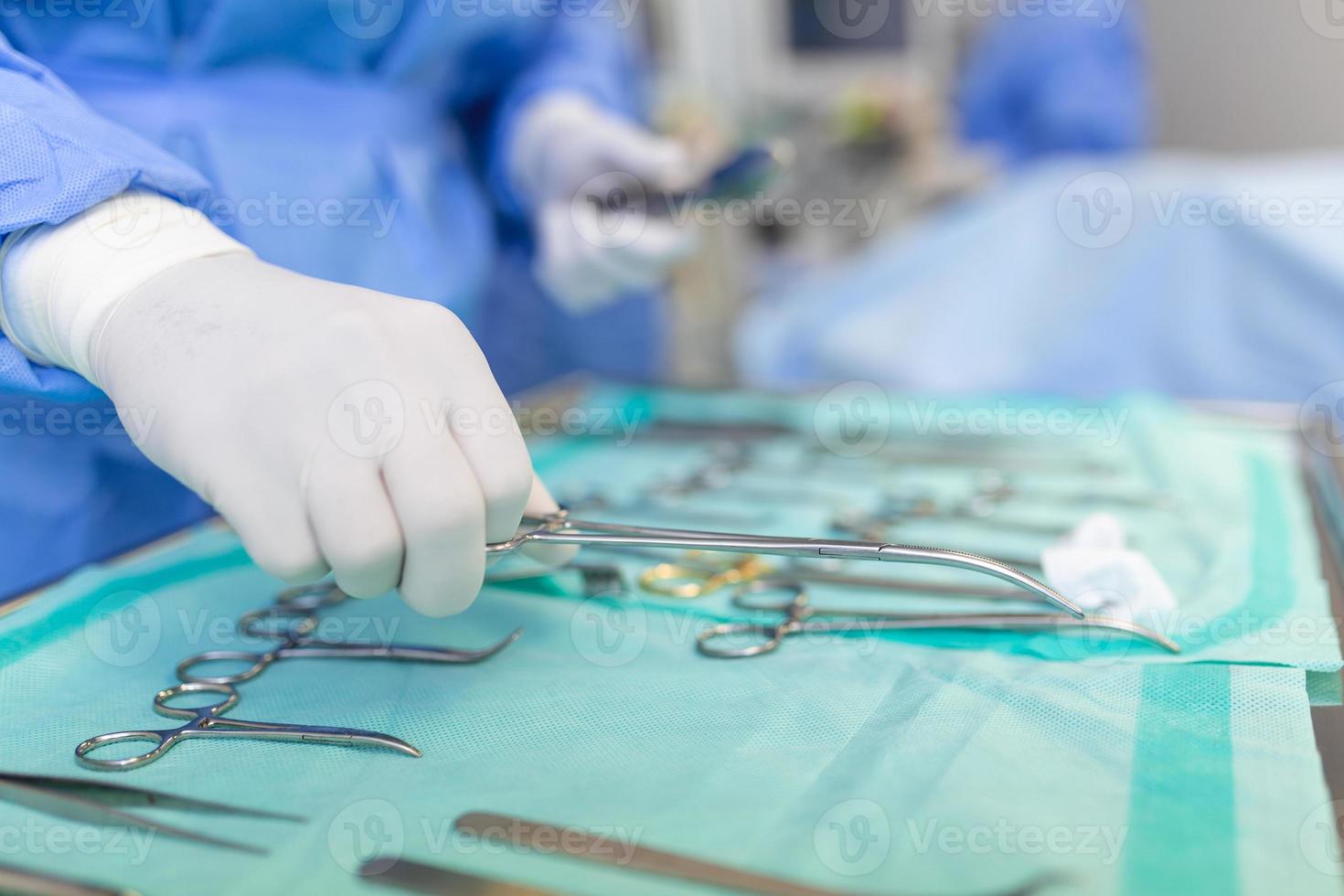 Operating Room of Surgical Table with Instruments, Assistant Picks up Instruments for Surgeons During Operation. Surgery in Progress. Professional Medical Doctors Performing Surgery. photo