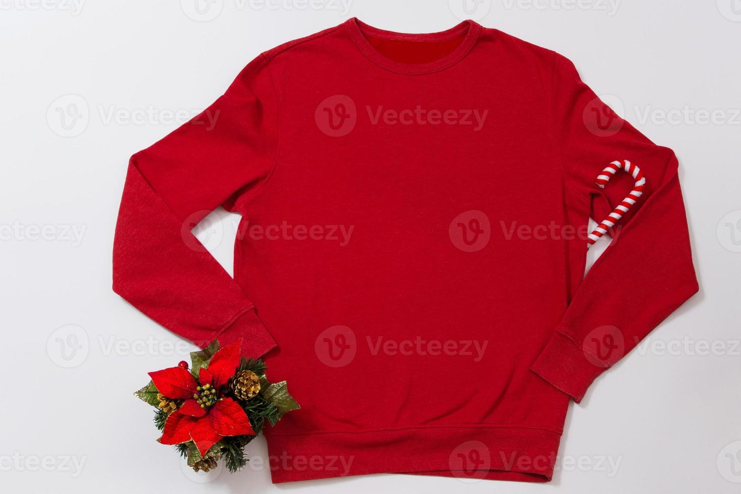 Close up red blank template sweatshirt with copy space and Christmas Holiday concept. Top view mockup hoodie and red holidays decorations on white background. Happy New Year accessories. Xmas outfit photo
