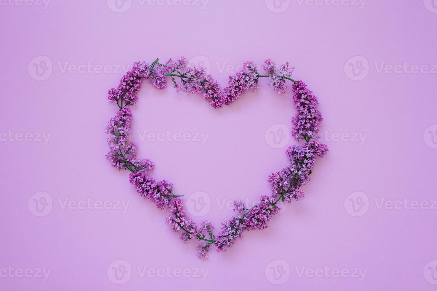 Heart shaped frame of lilac flowers on a colored background with a copy space. Valentine's Day, spring has come photo