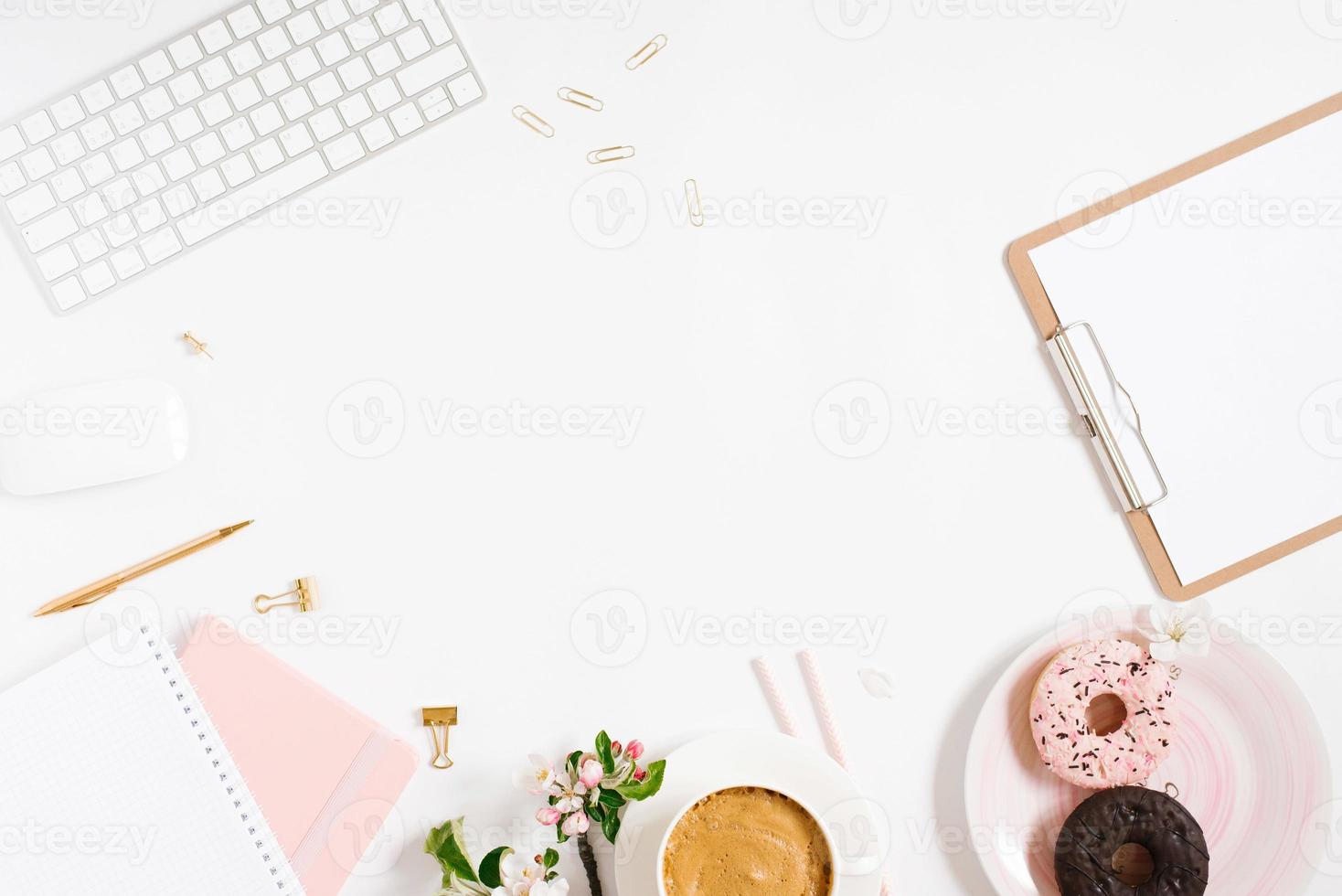 Trendy stylish frame for a female blogger, freelancer, notebooks, tablet, keyboard, donut on a plate, apple blossoms on a white background with a place to copy photo