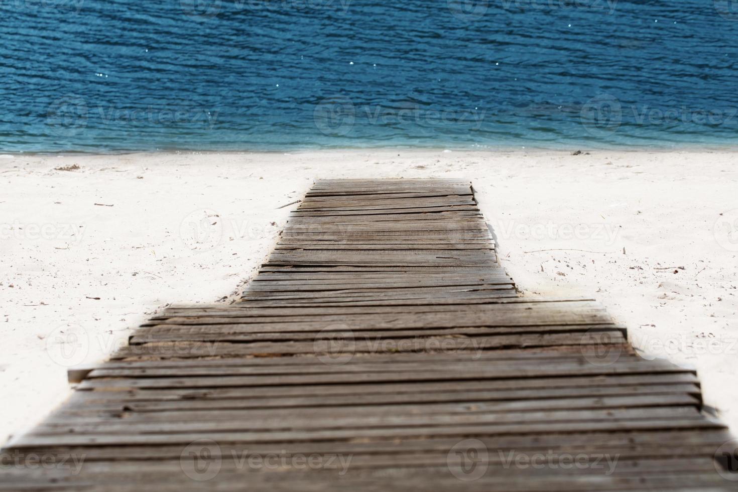 A wooden road runs down the beach to the sea. photo