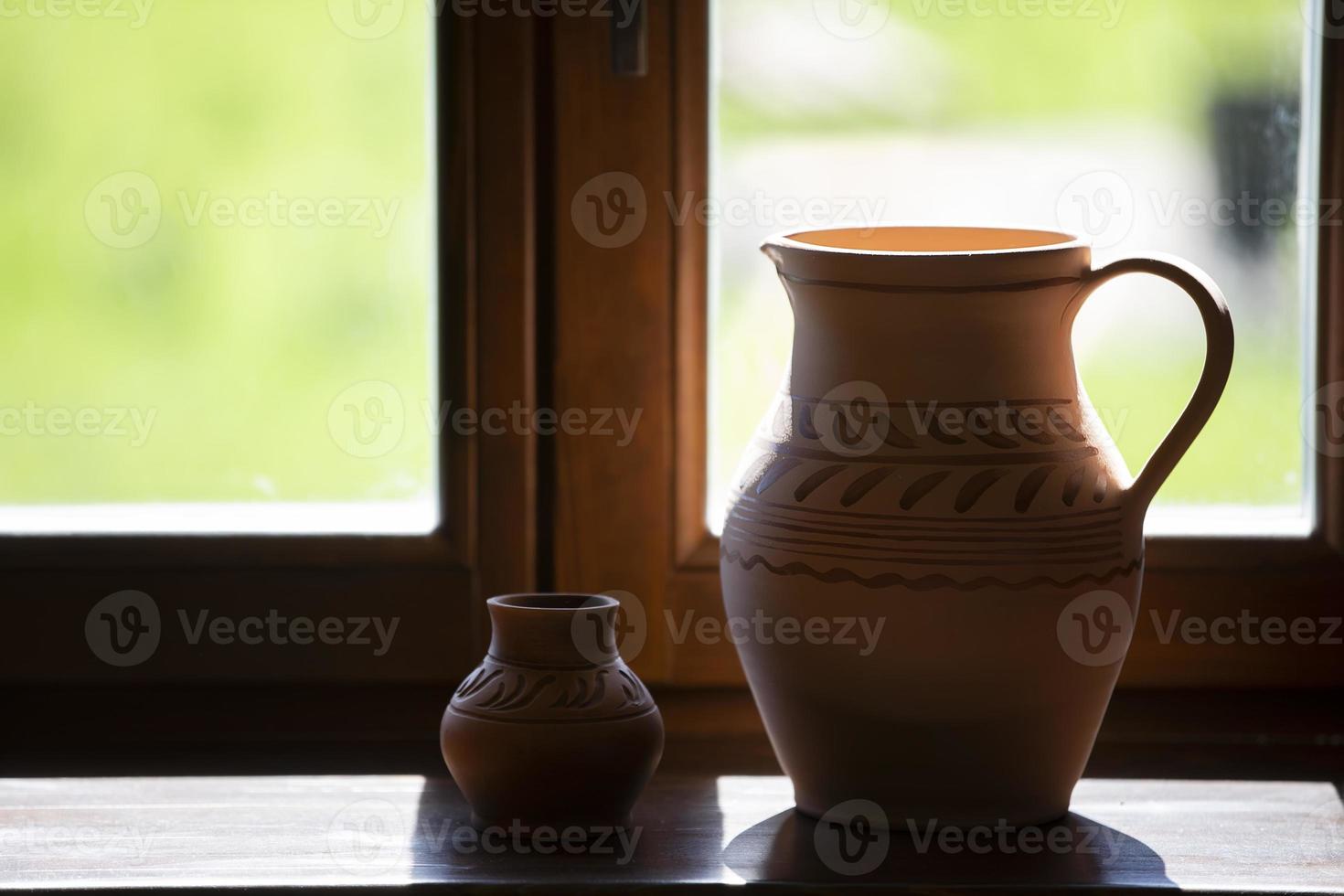 On the windowsill there are rustic clay jugs. photo