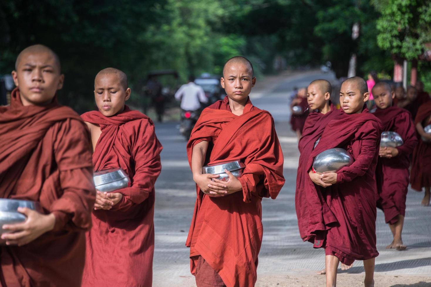 BAGAN, MYANMAR - JUL 18, 2018-Buddhist novices walk to collect alms and offerings along the road at Bagan, Myanmar. photo