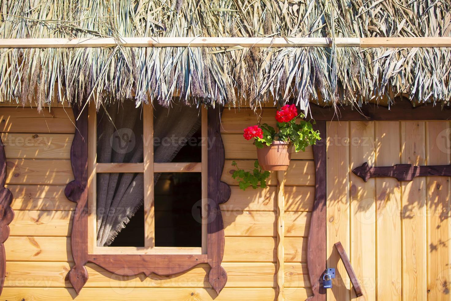 Background wood wall of a house with a window and a thatched roof. photo