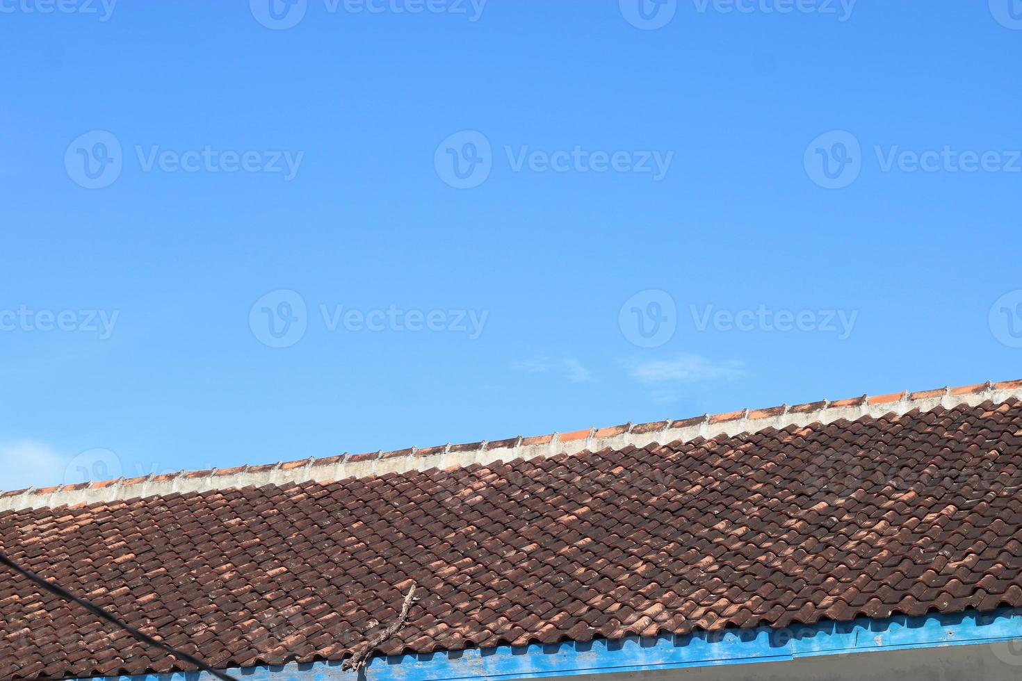 photo of the blue sky above the roof tiles of the house