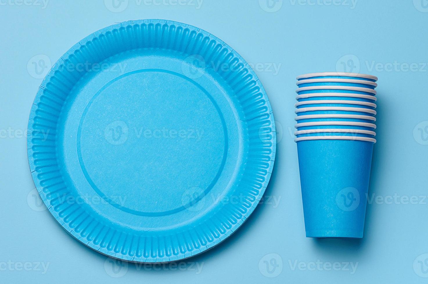 Round disposable blue paper plates and cups for a picnic, recyclable waste, top view. photo